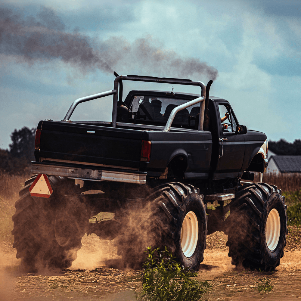 Potężny monster truck przemierza teren, wzniecając kurz i dym, co doskonale oddaje emocjonującą atmosferę atrakcji dostępnych zarówno dla dorosłych, jak i dzieci koło Warszawy.