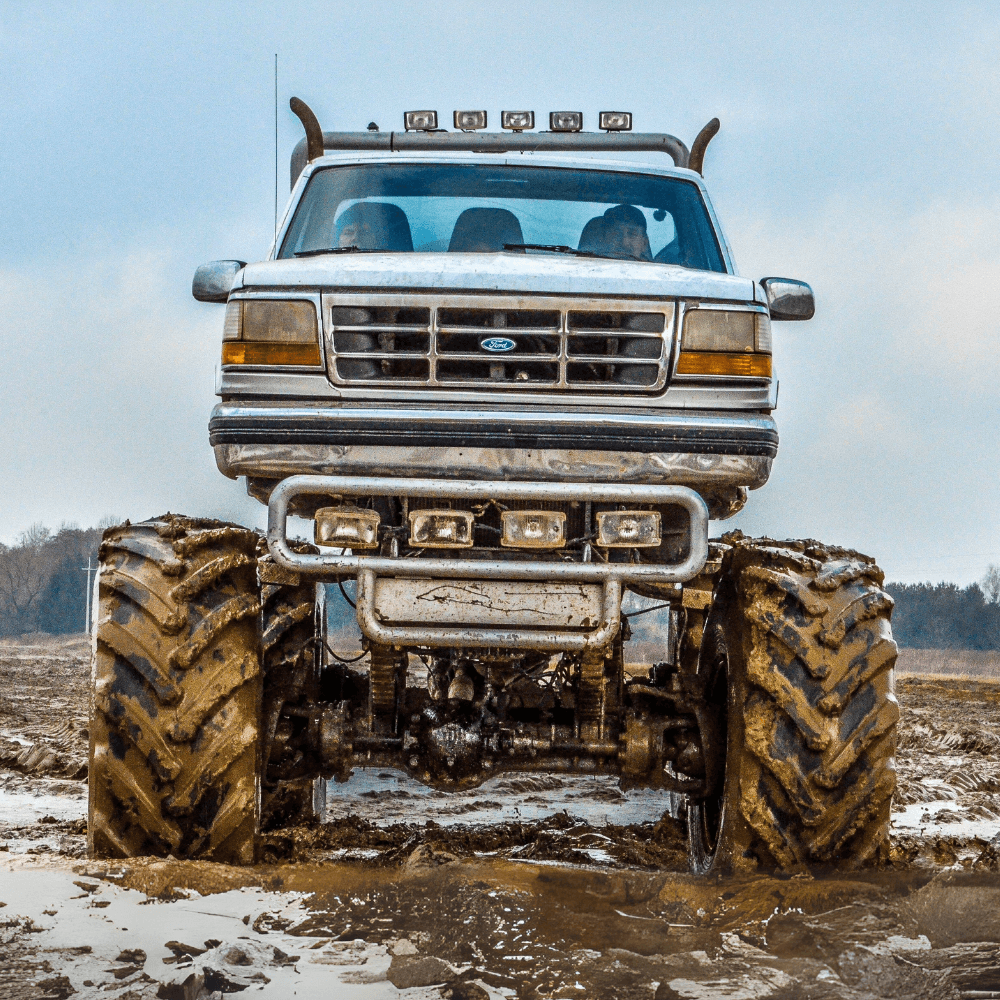 Potężny monster truck z ogromnymi oponami stoi gotowy do pokonywania błotnistych terenów.
