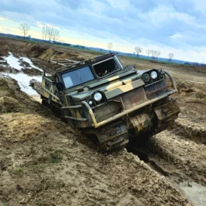 Na zdjęciu widać masywny pojazd gąsienicowy pokonujący błotnisty i wymagający teren, idealny przykład ekstremalnych atrakcji off-roadowych dostępnych w okolicach Warszawy.