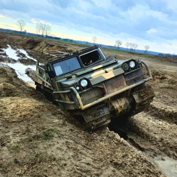 Na zdjęciu widać masywny pojazd gąsienicowy pokonujący błotnisty i wymagający teren, idealny przykład ekstremalnych atrakcji off-roadowych dostępnych w okolicach Warszawy.