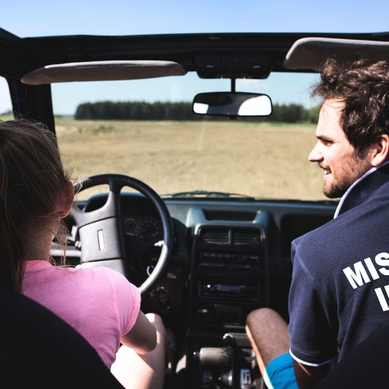 Rodzinna przygoda w terenie, gdzie młoda dziewczynka prowadzi pojazd terenowy pod okiem dorosłego, ciesząc się emocjami off-roadowej jazdy.