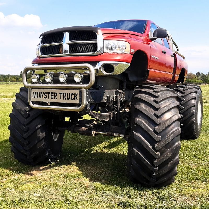 Na zdjęciu widać potężnego, czerwonego monster trucka na trawiastym tle, idealnego dla fanów emocji zarówno młodych, jak i dorosłych, w pobliżu Warszawy.