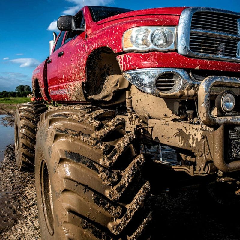 Na grafice widać potężny, błotem pokryty monster truck w dynamicznej scenerii, który emanuje ekscytacją i przygodą typową dla atrakcji zarówno dla dorosłych, jak i dzieci.