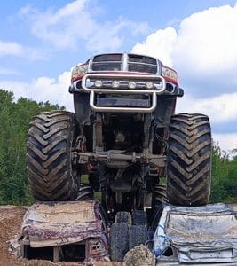 Wielki monster truck efektownie rozgniata wraki samochodów, podkreślając potęgę i emocje towarzyszące tego typu atrakcjom w Gassy pod Warszawą.