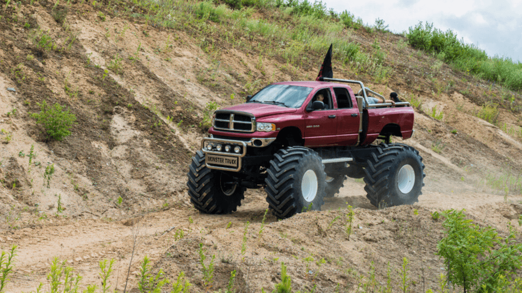 Ogromny monster truck sunie po piaszczystym terenie, przyciągając uwagę miłośników motoryzacyjnych atrakcji w Gassy pod Warszawą.