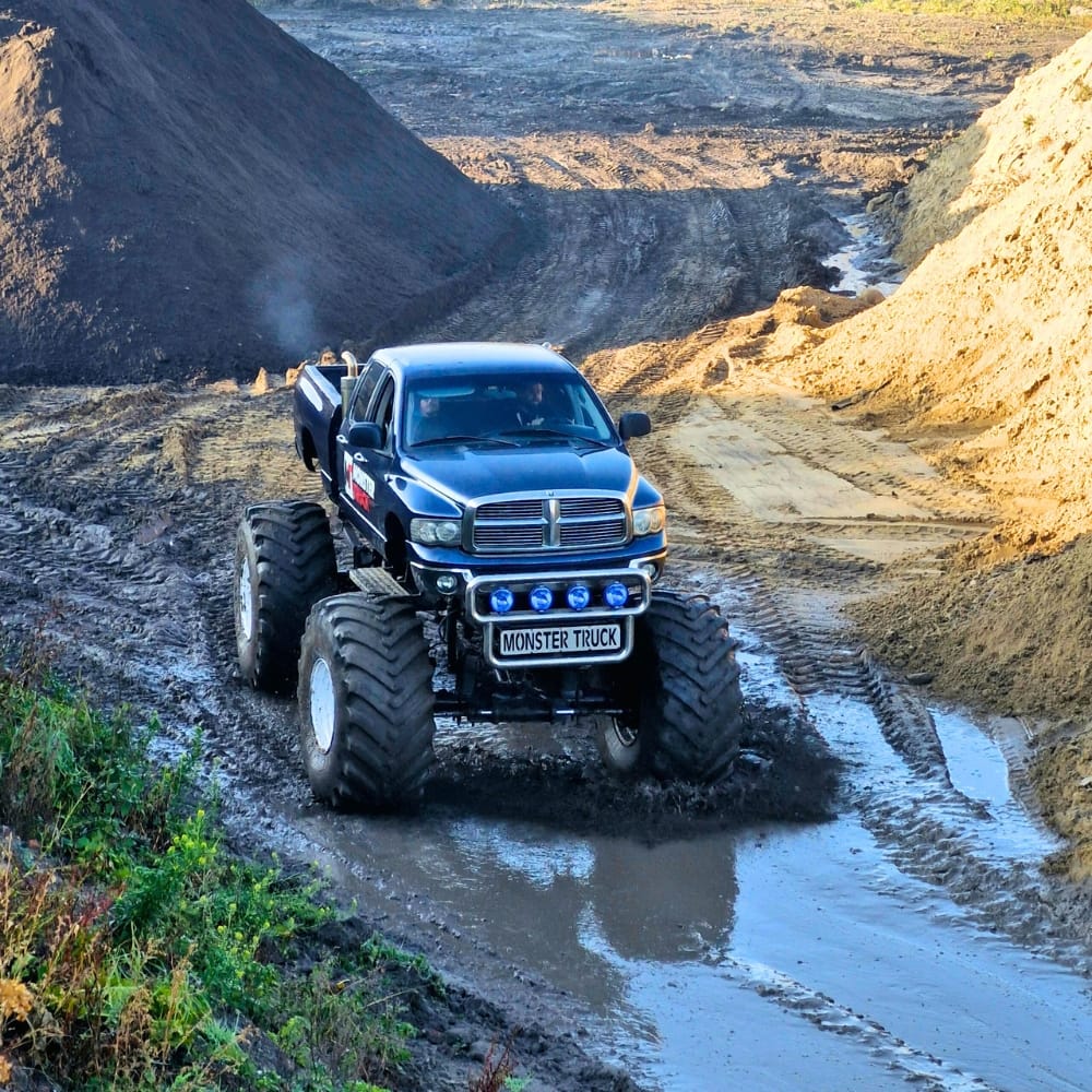 Ogromny monster truck pokonuje błotnisty teren, zapewniając emocjonujące przeżycia zarówno dla dzieci, jak i dorosłych.