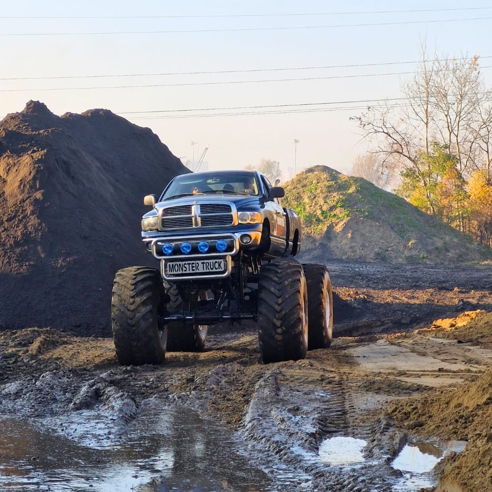 Monster truck przemierza błotnisty teren w pobliżu Warszawy, oferując emocjonujące atrakcje dla entuzjastów motoryzacji w każdym wieku.