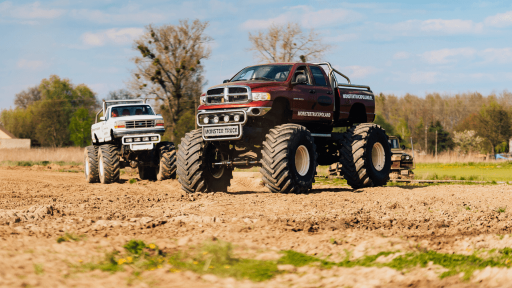Na zdjęciu widać potężne monster trucki manewrujące po torze terenowym, idealnym dla miłośników ekstremalnych przygód w Gassy pod Warszawą.