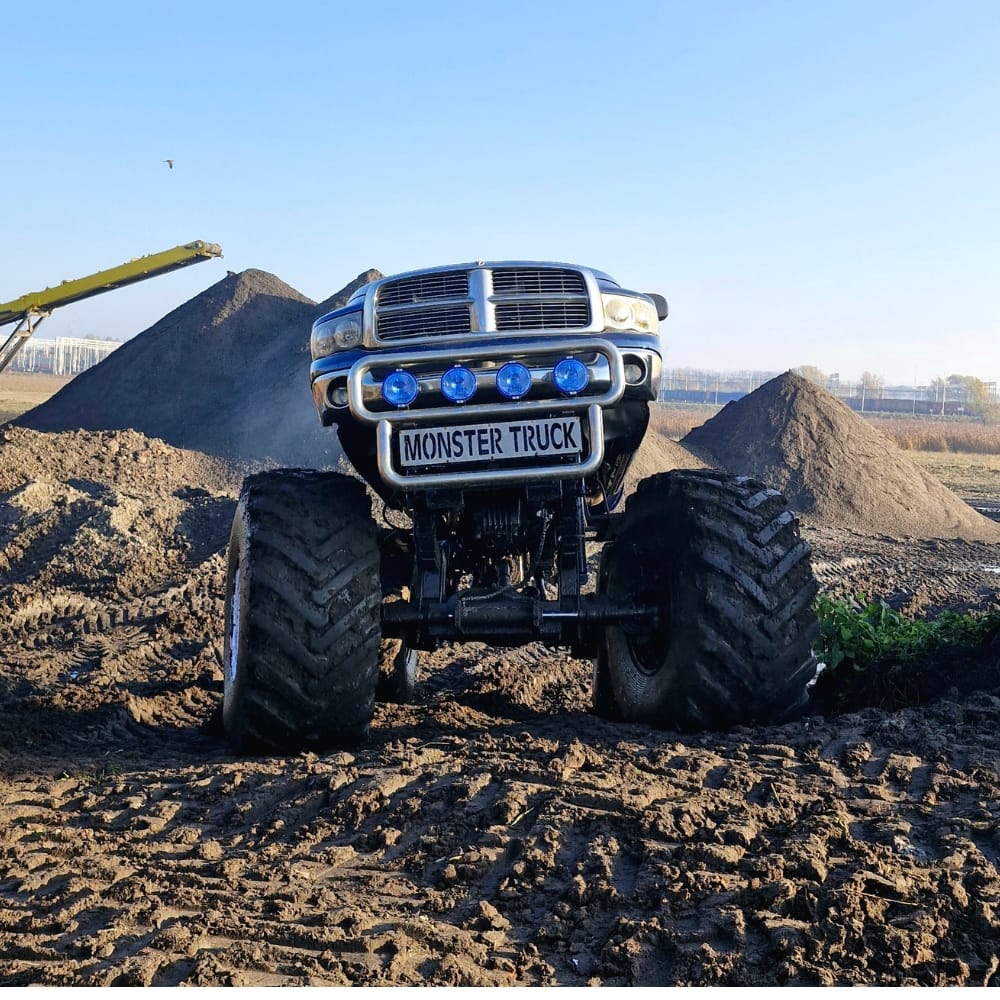 Na zdjęciu widzimy imponujący monster truck ustawiony na nierównym, piaszczystym terenie, gotowy na pełne emocji pokazy w Gassy koło Warszawy.