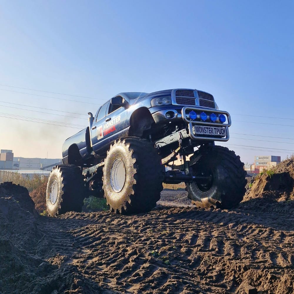 Na zdjęciu widać potężny monster truck w akcji na piaszczystym terenie, symbolizujący ekscytujące atrakcje dostępne dla wszystkich miłośników tej rozrywki w Gassy pod Warszawą.