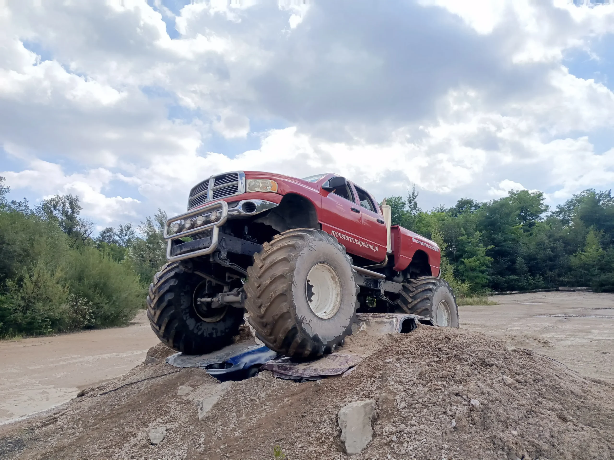 Czerwony Monster Truck przejeżdżający po wrakach samochodów